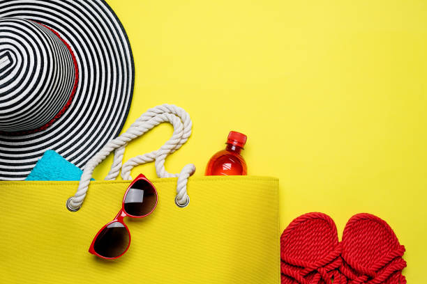 istock Yellow Beach Bag, striped hat and other beach stuff on yellow background 1313475929