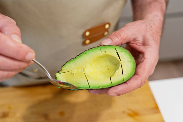 istock horizontal view of unrecognizable person cutting an avocado in the kitchen. 1313476664