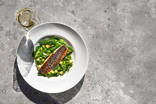 Grilled sea bass fillet and avocado with green beans, delicious diet food. bright sunshine with shadows