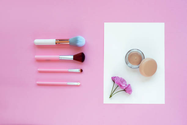 istock Makeup concealer and brushes. Cosmetic professional tools on pink background, top view, flat lay 1313480361