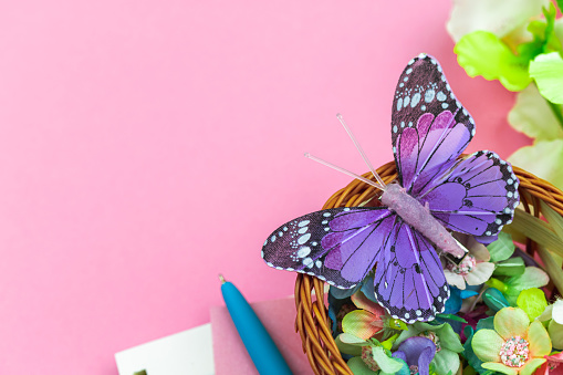 Spring and holiday workspace, pink background with flowers and butterfly, concept of mothers day greeting card