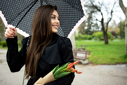 Business, weather, spring and people concept- young beautiful woman with umbrella in the park.