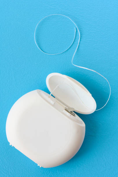 istock Container with dental floss close up on blue background 1313486438