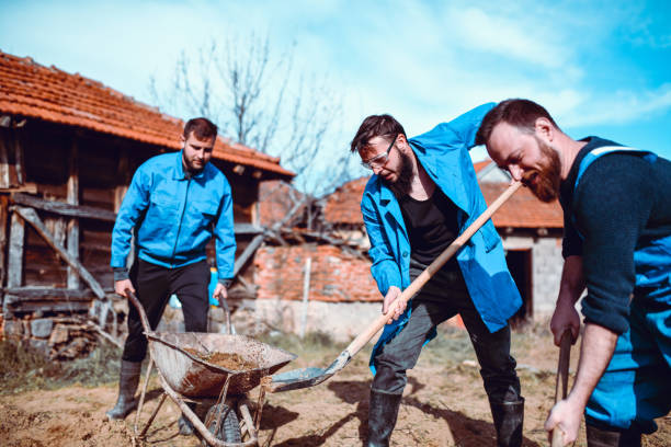 Farm Workers Digging Hole In Rural Backyard Area