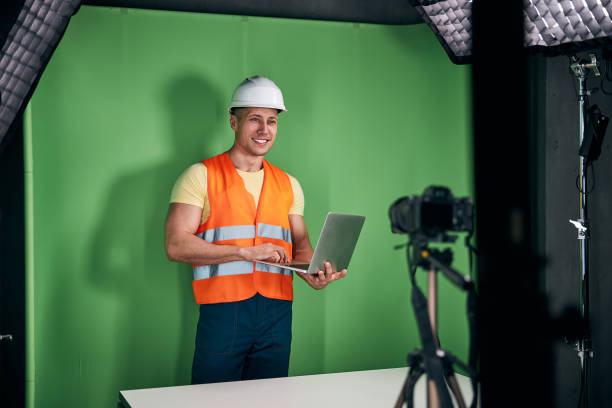 istock Joyful male builder using laptop and recording video 1313489224