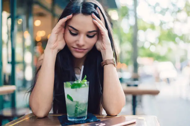 Depressed and worried female drinking alcohol cocktails after work