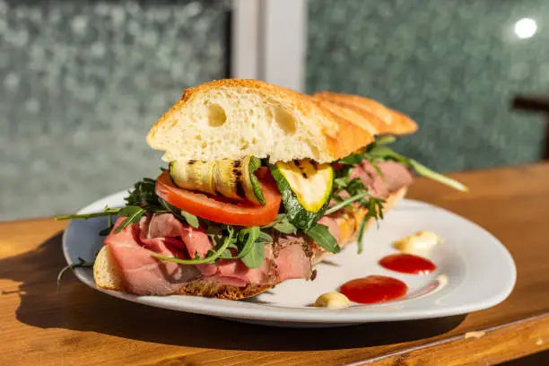 Bar sandwich with roast beef, grilled zucchini, tomato, rocket, ketchup