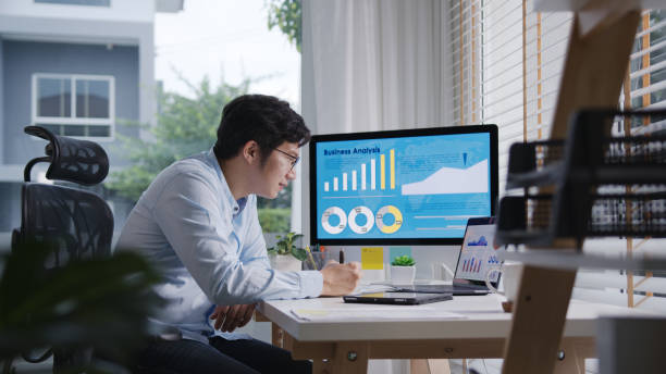 istock Candid of young attractive asian thai man busy work multiple screen computer or smart tablet on table desk at home in freelance data analyst, data science scientist for business. 1313497044