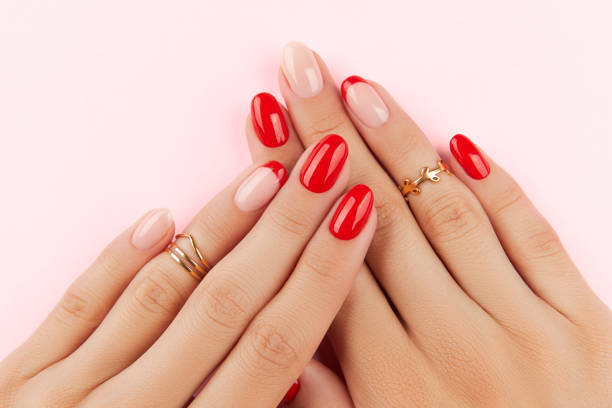 istock Womans hands with red modern manicure over pink background. Manicure design trends 1313499619