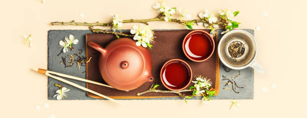 istock Asian Tea set on stone slate board, ceramic teapot, cups, dried tea and spring branches 1313502138