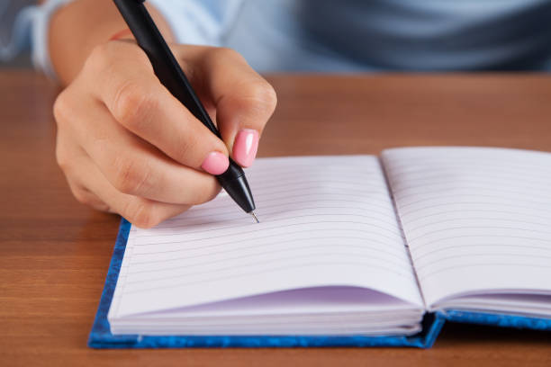 istock Woman writes in her notebook. Wooden table. 1313503195
