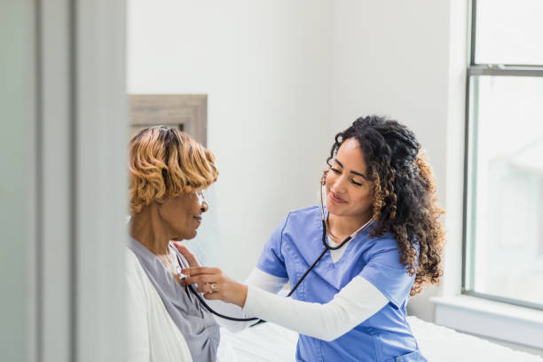 istock Cheerful nurse uses stethoscope to check patient's heart 1313504760