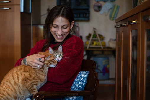 A mid adult woman introducing her newly adopted cat to her new home and existing pet.