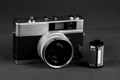 Monochrome vintage film rangefinder camera with roll of film