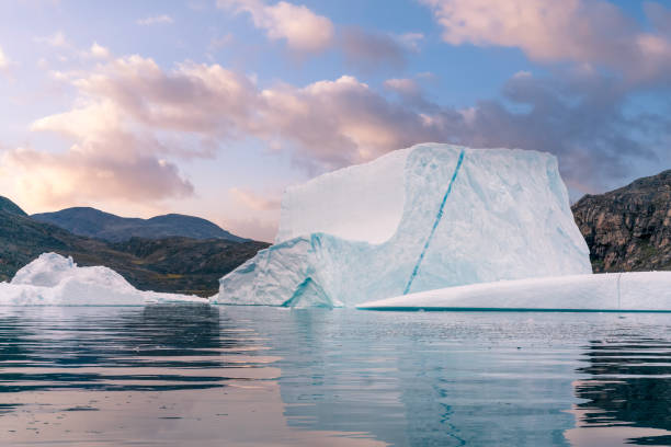 加拿大努納武特布勞頓島在水中反射的大藍冰山漂浮在海中。當天晚些時候從齊齊克塔爾朱阿克的因紐特人社區乘船。柔和發光的天空。 - 努勒維特地區 個照片及圖片檔