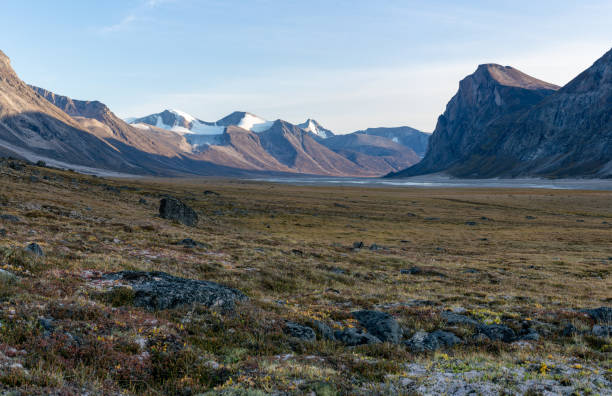 istock Monumental, wild arctic valley during sunset. Tall peaks with snow on top and river bed below. Duskfall at Akshayuk pass, Baffin Island, Canada. 1313509053