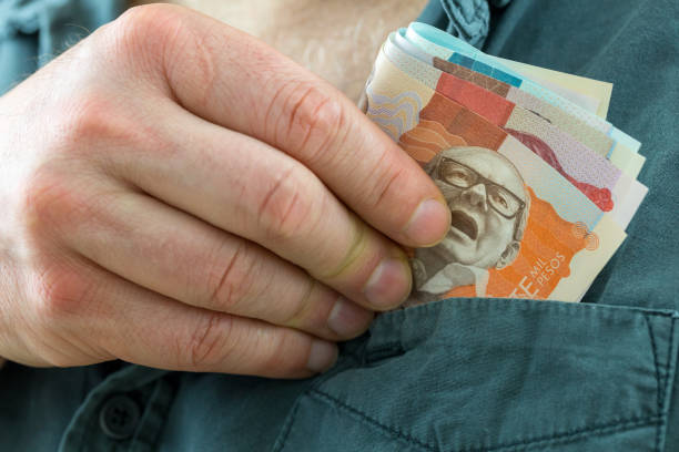 the man takes a bundle of columbian pesos from his shirt pocket the man takes a bundle of columbian pesos from his shirt pocket colombian peso stock pictures, royalty-free photos & images