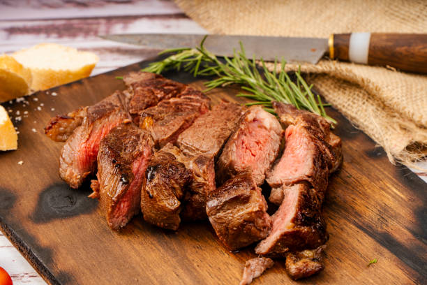 churrasco aus fleisch in stücke geschnitten auf einem holzbrett in einer rustikalen umgebung. nahaufnahme, 45 grad ansicht - steak argentina food silverware stock-fotos und bilder