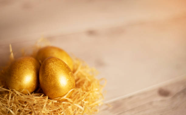istock three golden easter eggs in a nest on a wooden table 1313510434