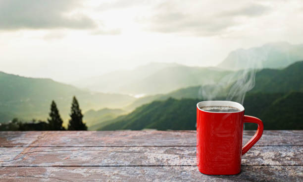 istock freshly brewed coffee or espresso into a red cup and coffee mug. Hot coffee in a mug placed on the tabletop or wooden balcony. Morning mountain view, morning sunshine. 3D Rendering 1313511315