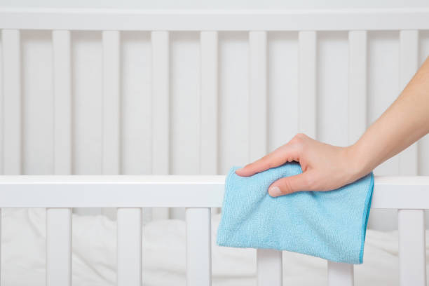 젊은 성인 여성 손 들고 파란색 마른 걸레와 침실에서 흰색 침대의 가장자리를 닦아. 근접 촬영. 측면 보기입니다. - baby wipe rubbing cleaning human hand 뉴스 사진 이미지