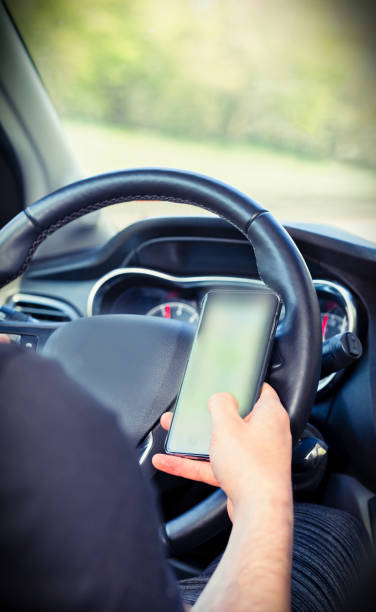 młody kierowca człowiek za pomocą telefonu komórkowego w samochodzie, ręka trzymając inteligentny telefon i jazdy i sms-ów, koncepcja biznesu transportu - driving text messaging accident car zdjęcia i obrazy z banku zdjęć