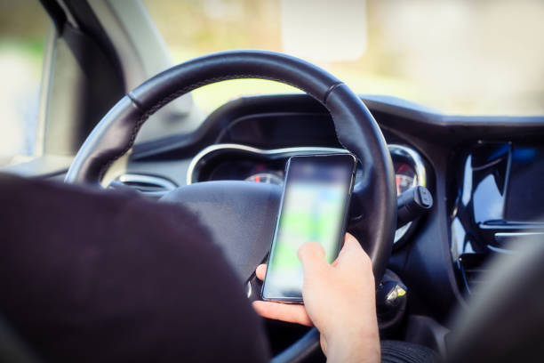 istock Young man driver using mobile phone in car, hand holding smart phone and driving and texting, transport business concept 1313512783