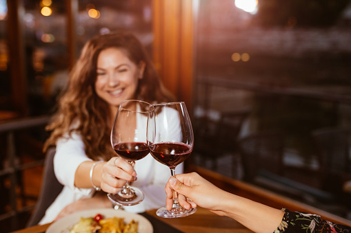 Close up of toasting with glasses of red wine at restaurant