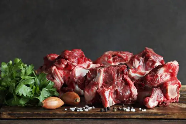 Raw beef bones, vegetables and herbs. Ingredients for making beef broth.