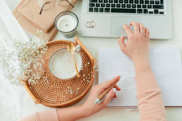 istock Home office, work, female hands, cappuccino, wicker tray, spring, home decor, laptop, notebook. Cozy. 1313514456