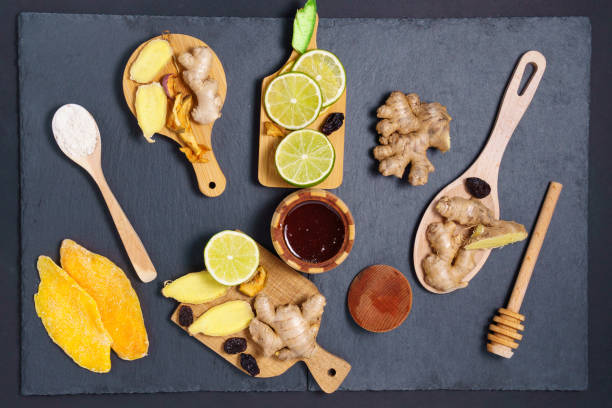 cibo e bevande, concetto di assistenza sanitaria. frutta secca allo zenzero, lime al miele, mango e ingredienti su un tavolo in pietra grunge nera. sfondo spazio di copia - ginger root ingredient nature foto e immagini stock