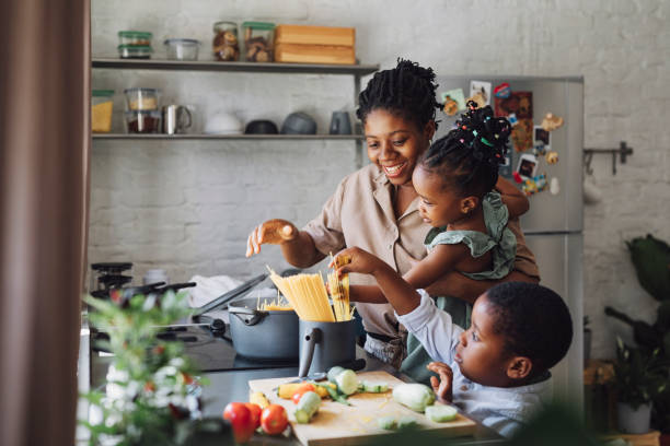 Mother, Daughter and Son Preparing Spaghetti and Vegetables for Lunch Happy African American mother, daughter and son preparing spaghetti and vegetables for lunch family dinners and cooking stock pictures, royalty-free photos & images