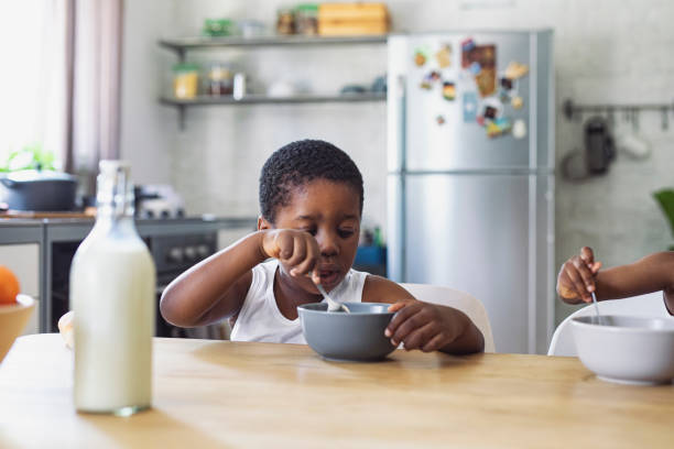 istock Happy Young Boy Eating Cereals with Milk for Breakfast in A Kitchen 1313518703