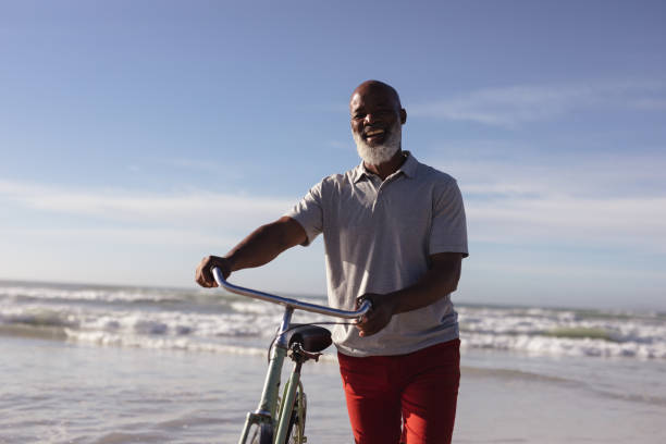istock Senior african american man with bicycle smiling while walking together on the beach 1313521098