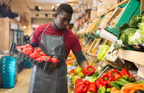 istock Salesman filling counter with red peppers 1313524953
