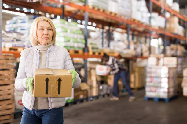 istock Female warehouse worker carrying cardboard boxes 1313524972