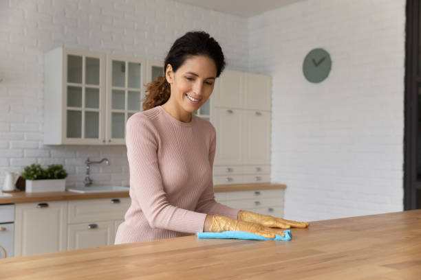 glückliche millennial latin frau hausfrau wischen staub von derküche - cleaning domestic kitchen counter top housework stock-fotos und bilder