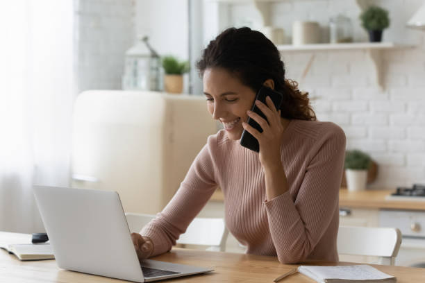 istock Young woman specialist sit by laptop give consultation using cell 1313525187