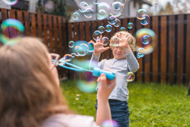 istock Caucasian Mother Blowing Bubbles with Her Son in Backyard 1313527674