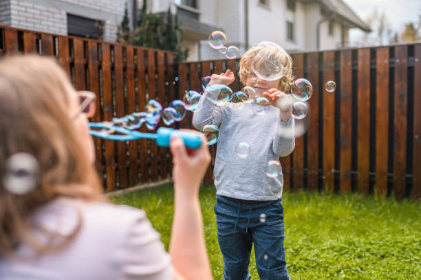 istock Caucasian Mother Blowing Bubbles with Her Son in Backyard 1313527676