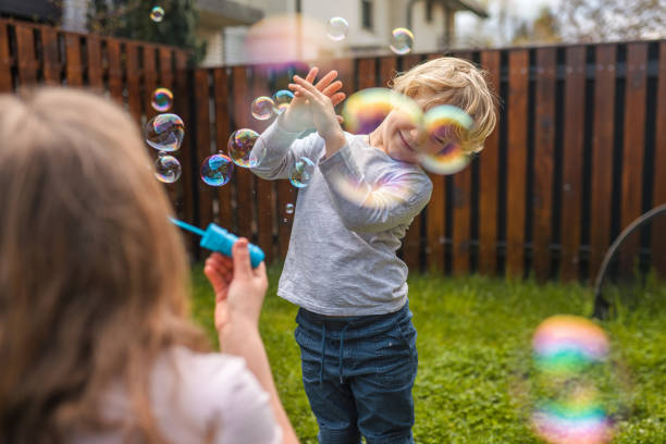 istock Caucasian Mother Blowing Bubbles with Her Son in Backyard 1313527683