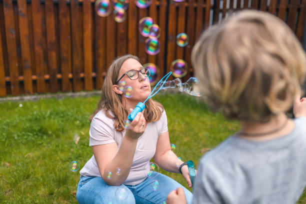istock Caucasian Mother Blowing Bubbles with Her Son in Backyard 1313527696