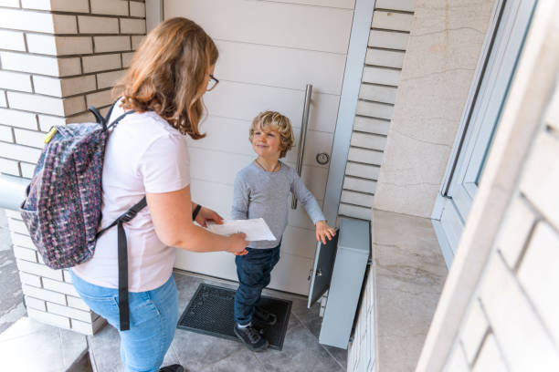 Happy postman putting envelope into mail box outdoors