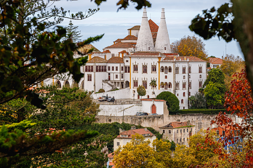Sintra, Portugal - October 28, 2020: Architectural detail of the National Palace of Sintra, also called the Royal Palace with its 2 chimneys of 33 meters behind trees on a winter day