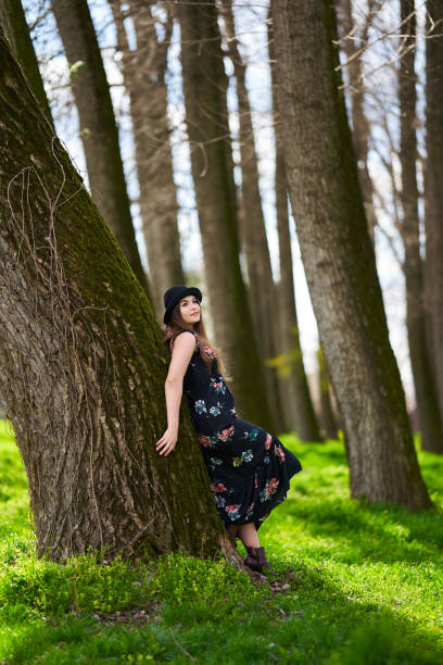 Young woman enjoying a stroll through the park in the early spring fresh green grass among the big trees