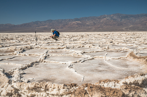 Tourist taking photos, Salt Flats in Death Valley National Park. Trail adventure through upheaved salt plates below sea level.