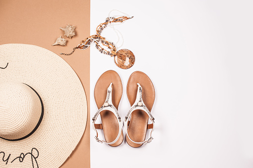 Woman Summer Personal Accessories with White Sandals and Straw Hat on White and Beige Background