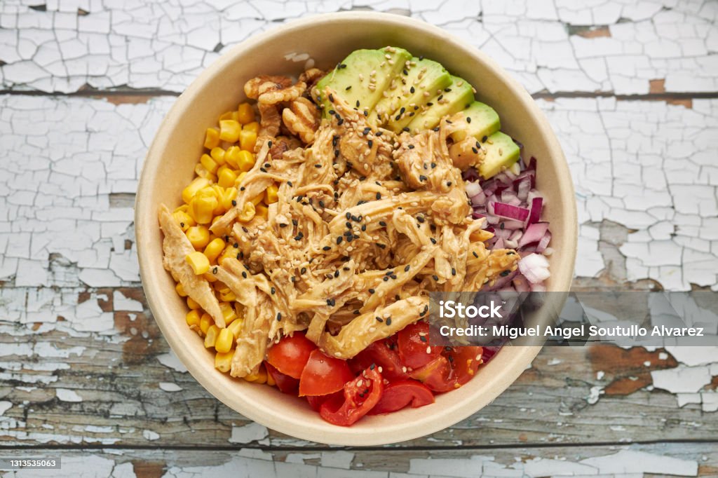Aerial view of an avocado chicken poke and cherry tomatoes. Corn Stock Photo