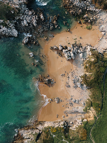 A drone aerial view of a small rocky beach on a sunny day