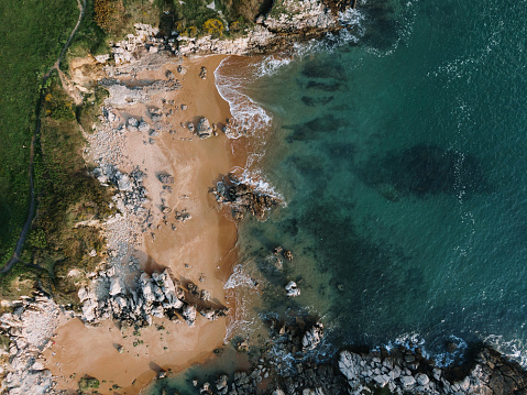 A drone aerial view of a small rocky beach on a sunny day